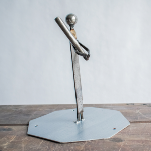 Side view of industrial metal baseball player sculpture with bat resting across the shoulder, showing relaxed yet powerful stance.