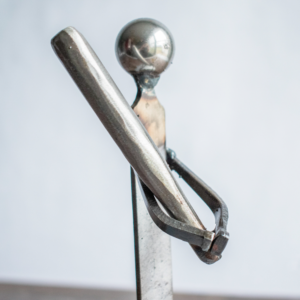Close-up of the baseball bat and arm of the welded metal baseball player sculpture, emphasizing strength and precision.