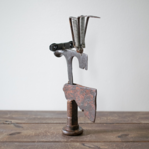 Side view of Mr. Hatchet industrial metal sculpture featuring a hatchet head torso and welded steel components.