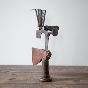 Three-quarter angle of Mr. Hatchet sculpture highlighting balance, character, and industrial metal construction.