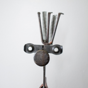 Front-facing close-up of Mr. Hatchet industrial metal sculpture emphasizing expressive character and raw materials.