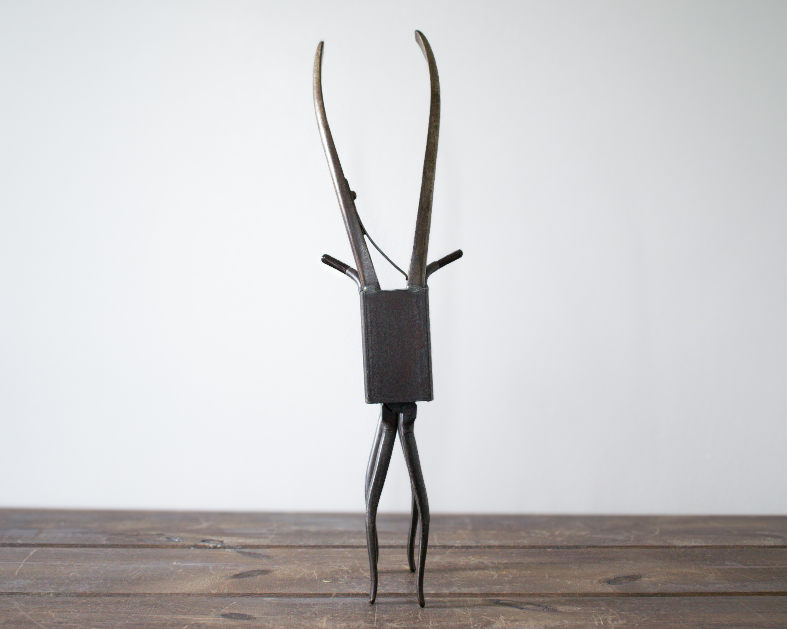 Welded metal antelope sculpture made from pliers and steel tubing standing on tabletop.