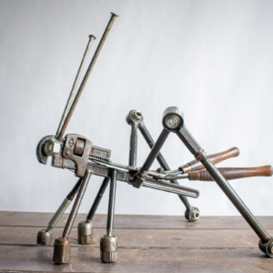 Metal grasshopper sculpture made from reclaimed steel, pipe wrench, shears, large nails, and car control arms.