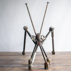 Front view of industrial garden art shaped like a grasshopper with long metal legs and antennae.