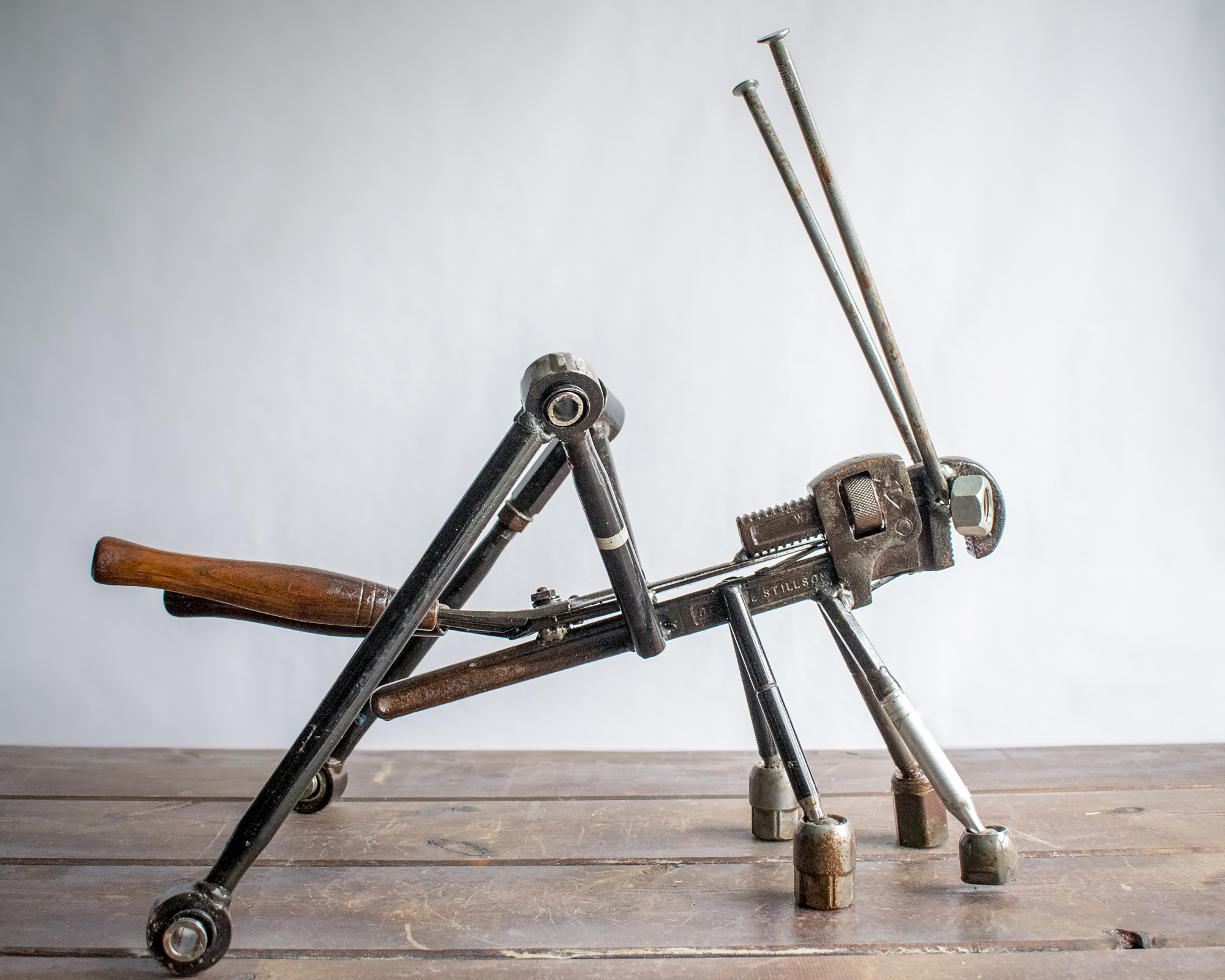 Side view of metal insect sculpture made from reclaimed tools and heavy-duty steel parts.