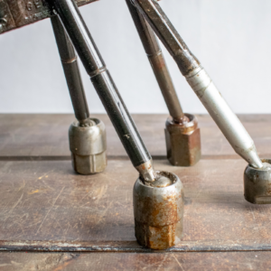 Close-up of reclaimed metal legs and textured steel feet on industrial garden art.