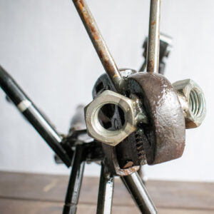 Close-up of grasshopper head detail made from pipe wrench, nuts, and welded steel parts.