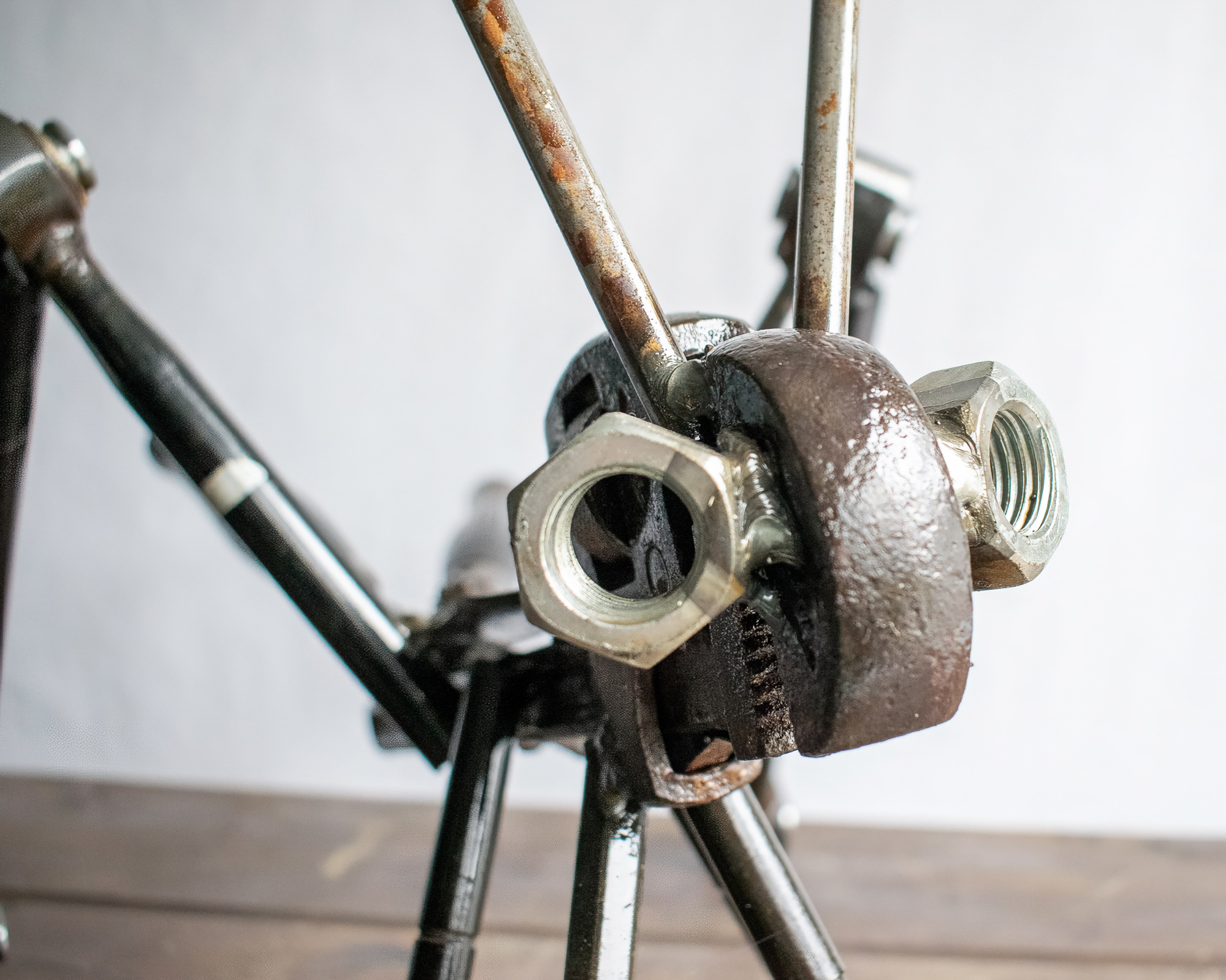 Close-up of grasshopper head detail made from pipe wrench, nuts, and welded steel parts.