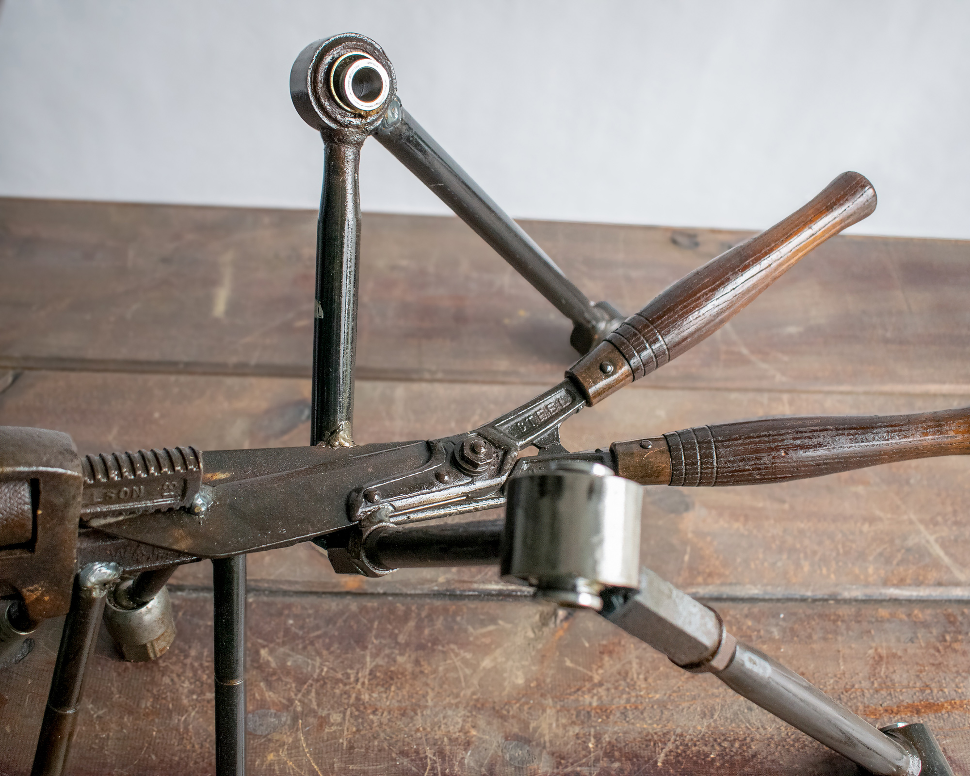 Close-up of wooden handle and car control arm details on a reclaimed metal insect sculpture.