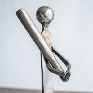 Close-up of the ball bearing head and metal bat on a metal baseball player sculpture.