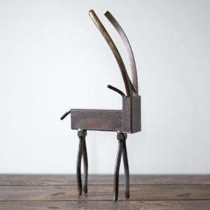 Side view of industrial animal art showing a metal antelope sculpture with curved plier horns.