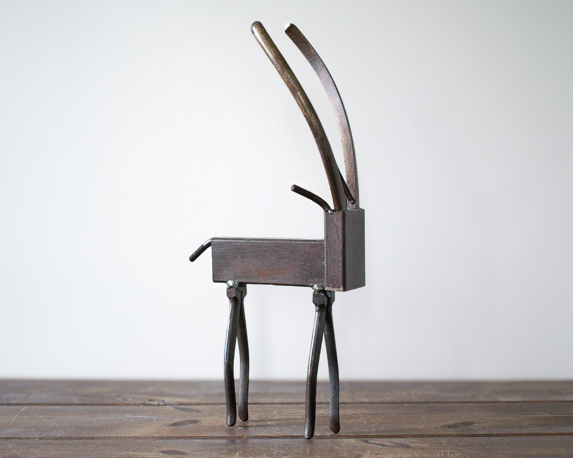 Side view of industrial animal art showing a metal antelope sculpture with curved plier horns.