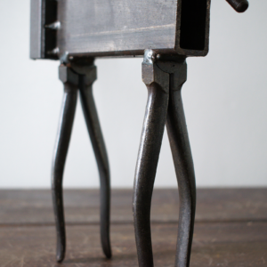 Close-up of the steel legs and welded body details on an industrial tabletop decor sculpture.