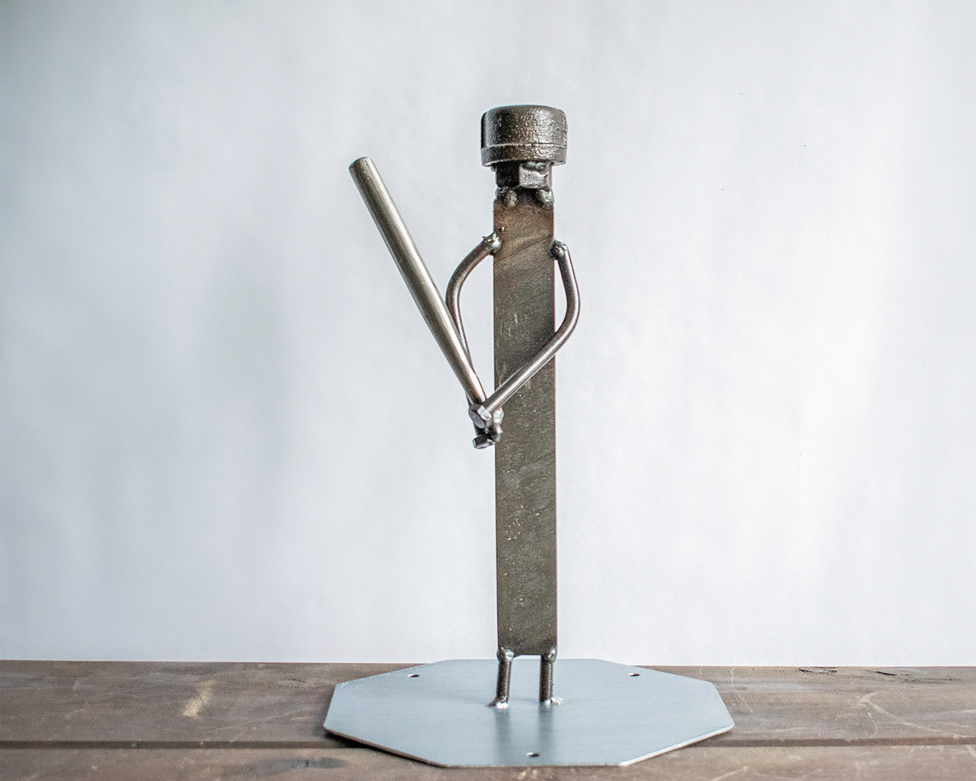 Metal baseball player sculpture made from a ball bearing, metal file, square-head nails, and reclaimed steel.