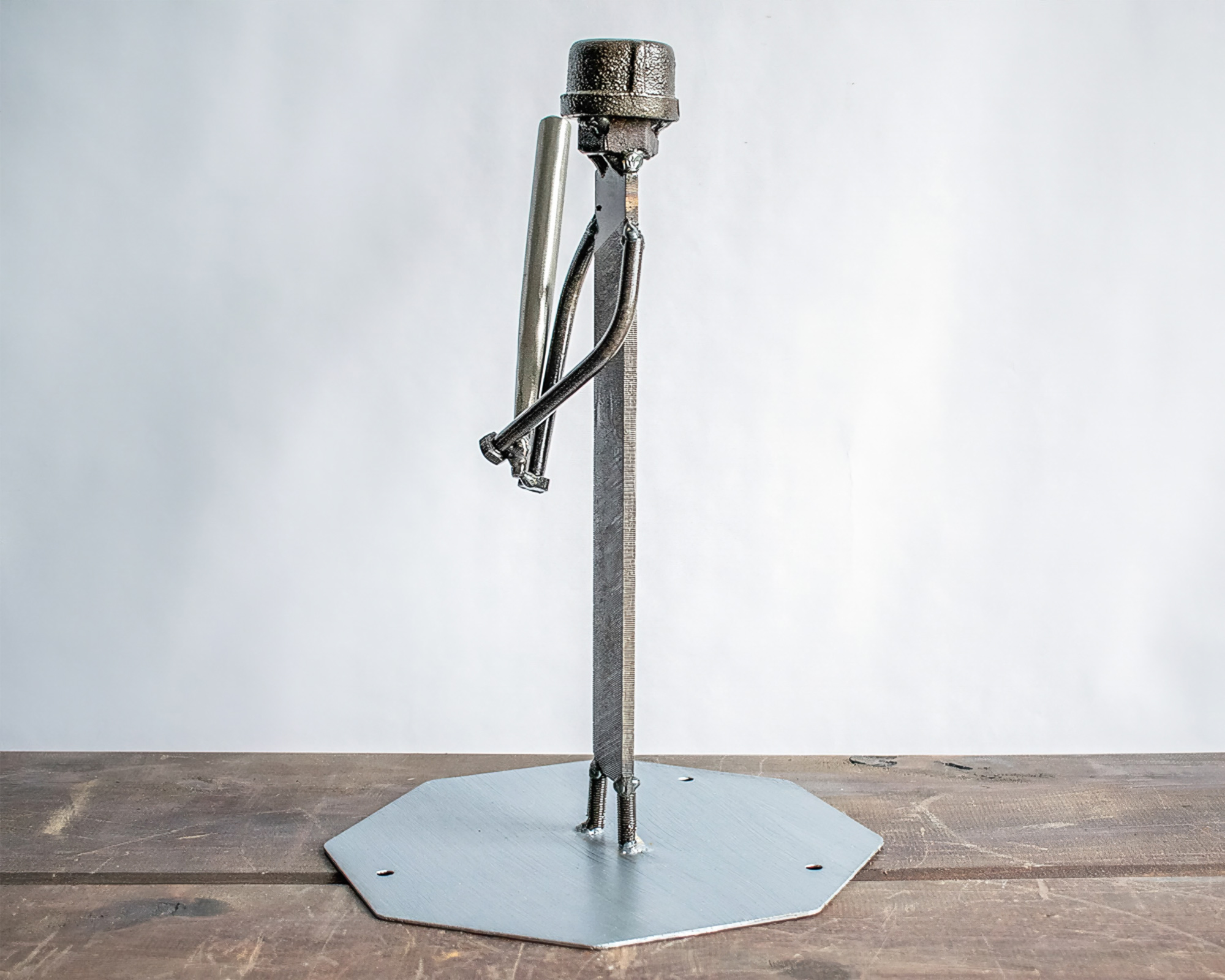 Side view of baseball metal art showing a handmade scrap metal figure holding a bat.