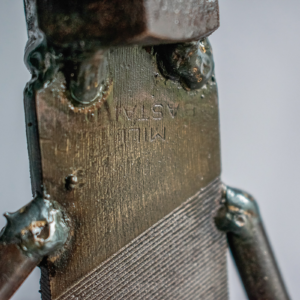 Close-up of the metal file body, welds, and raw steel texture on a welded metal sculpture.