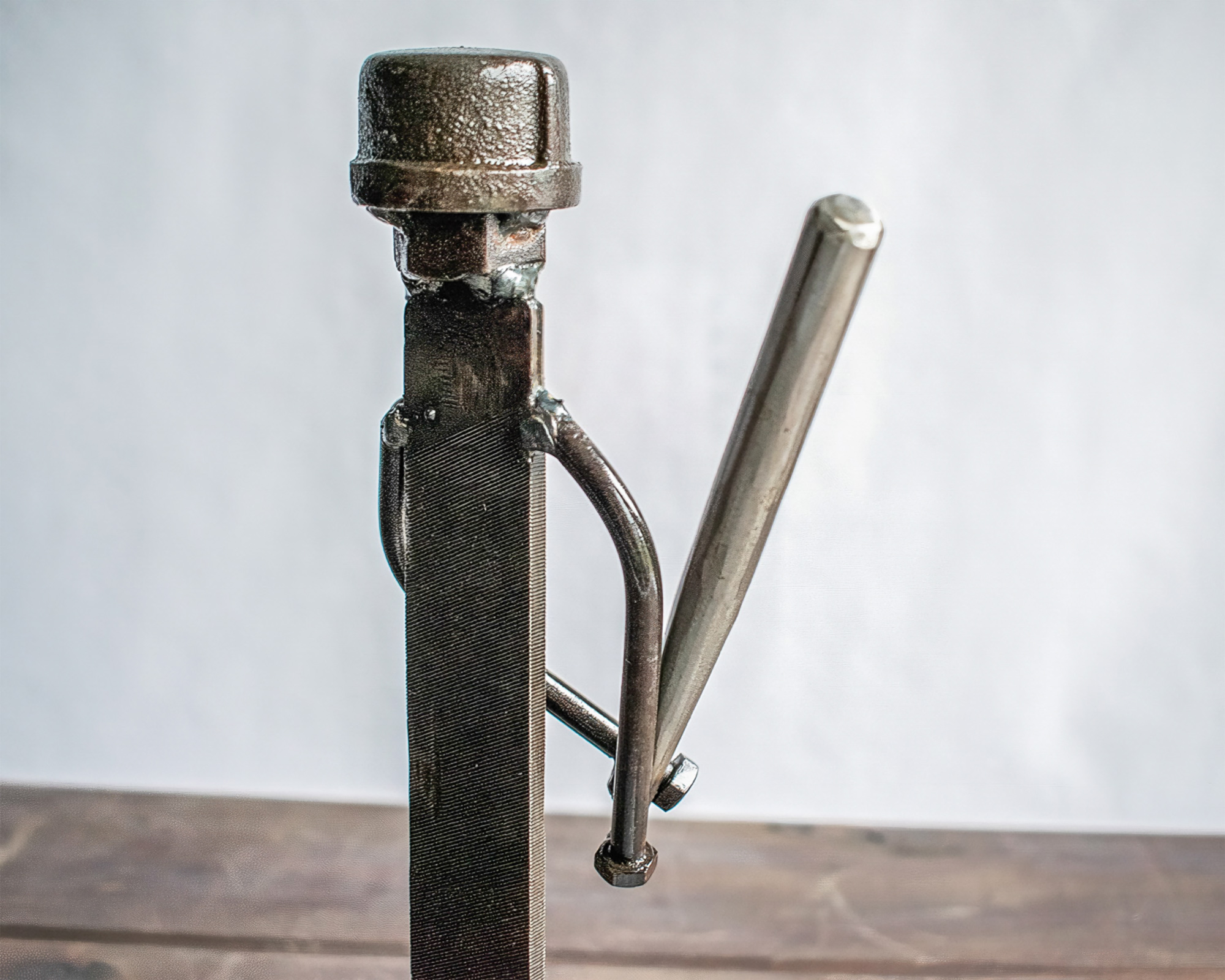 Close-up of baseball player sculpture with ball bearing head and welded metal bat detail.