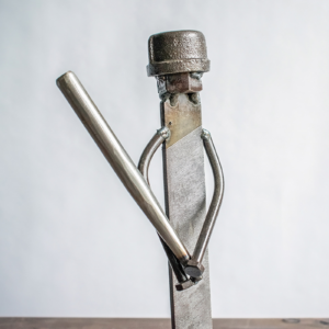 Front view of industrial sports decor showing a welded metal baseball player sculpture holding a bat.