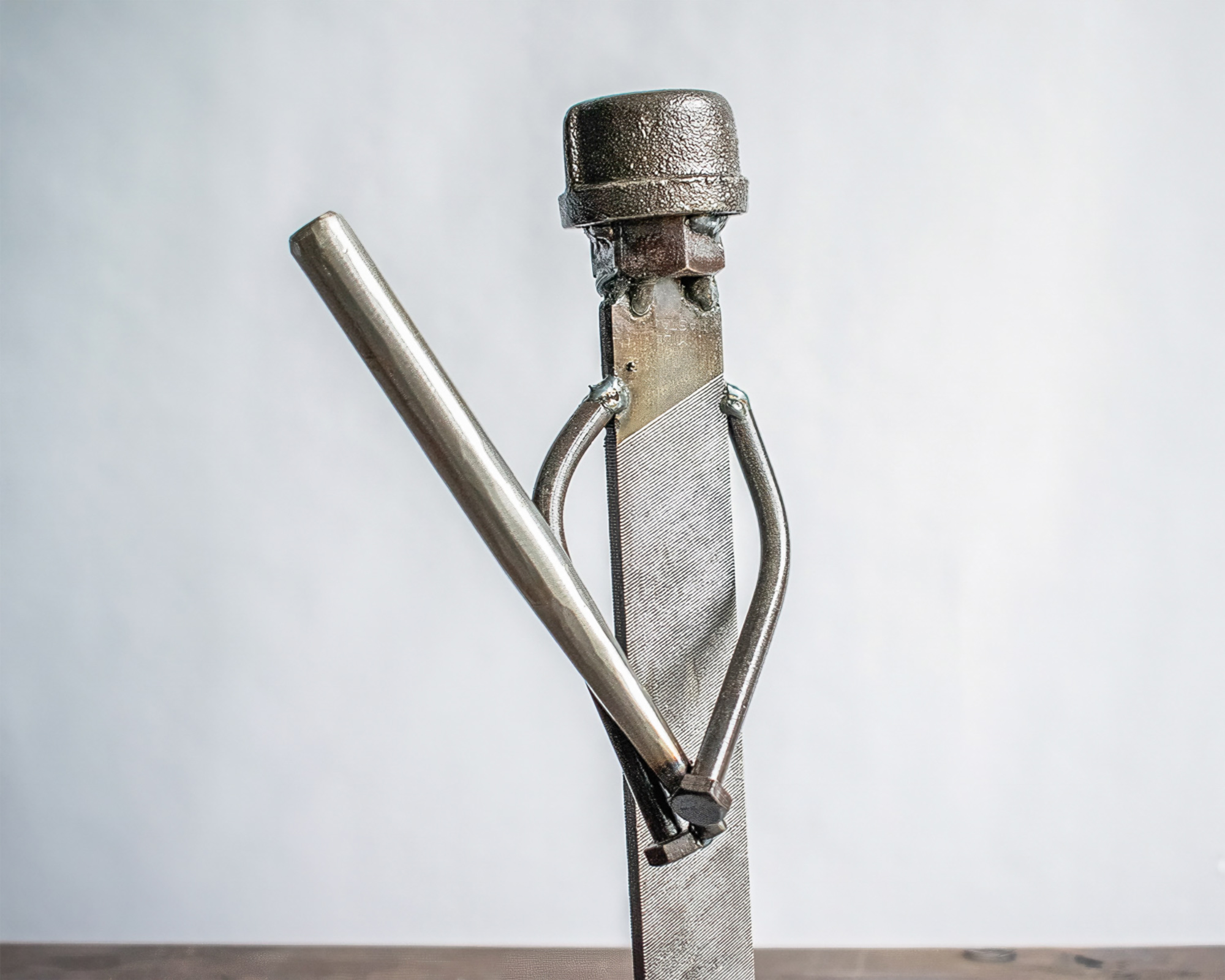 Front view of industrial sports decor showing a welded metal baseball player sculpture holding a bat.