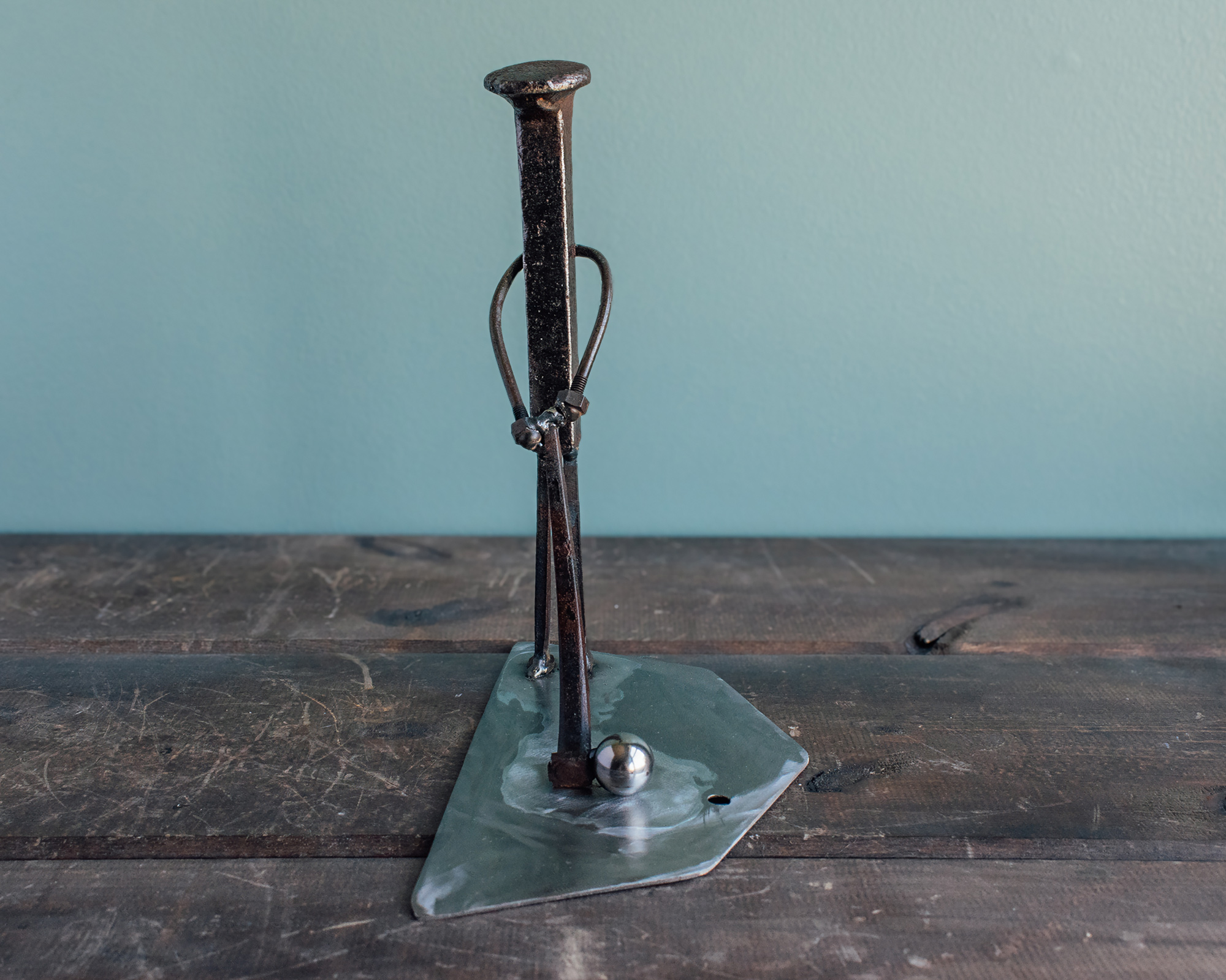 Front view of handmade golf metal art showing a golfer figure mid-swing with a steel ball bearing.