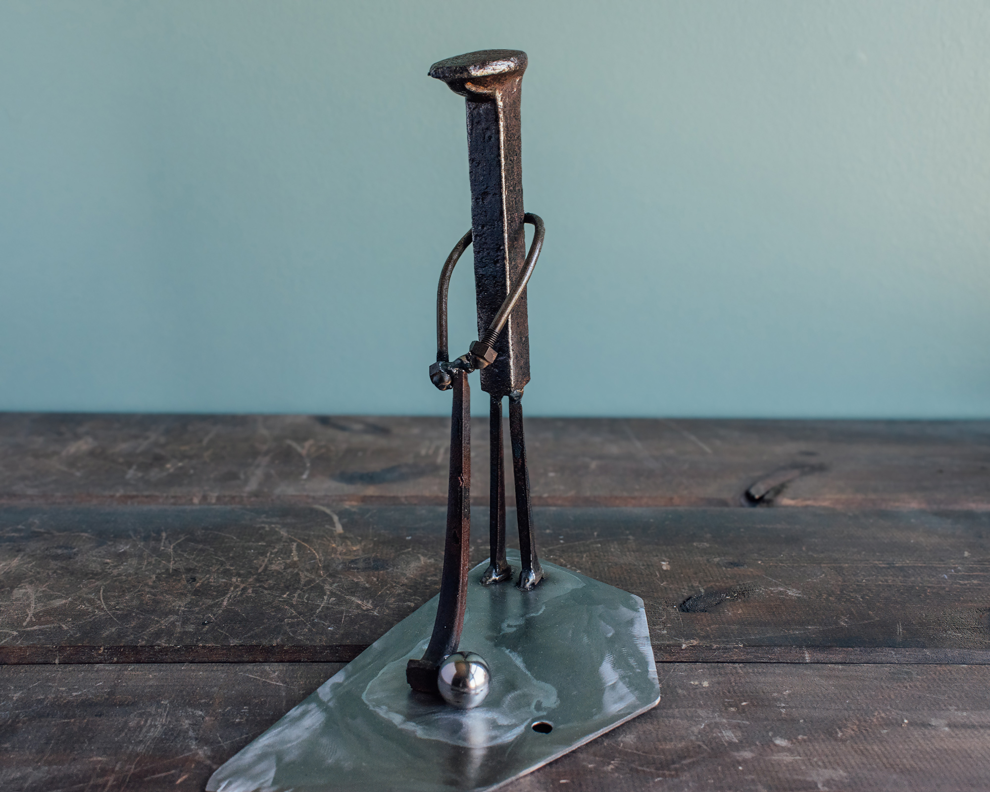 Angled view of welded metal golfer sculpture made from reclaimed steel with a simple swing pose.