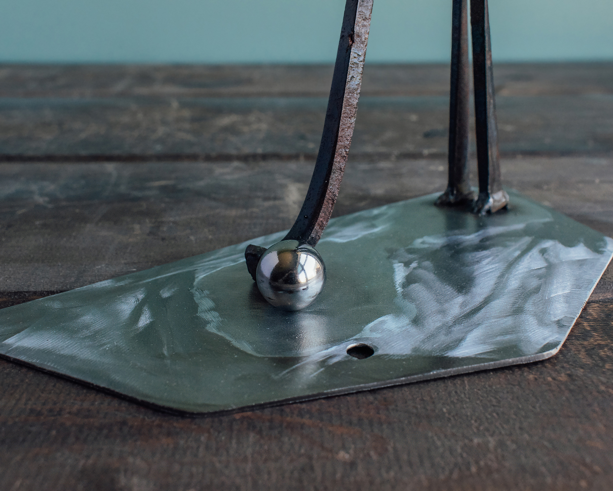 Close-up of ball bearing golf ball and steel base on a welded metal golfer sculpture.