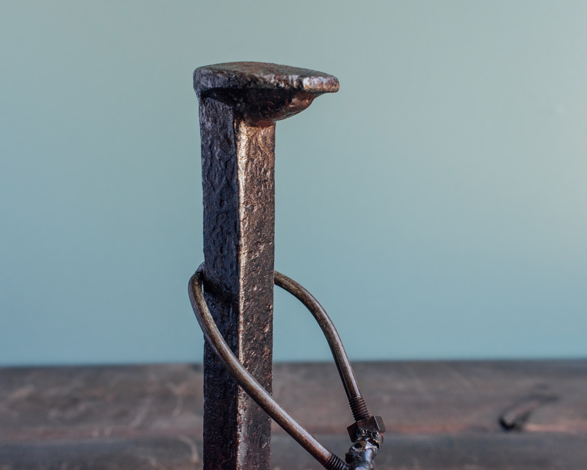 Close-up of railroad spike body and raw steel texture on handmade industrial golf decor.