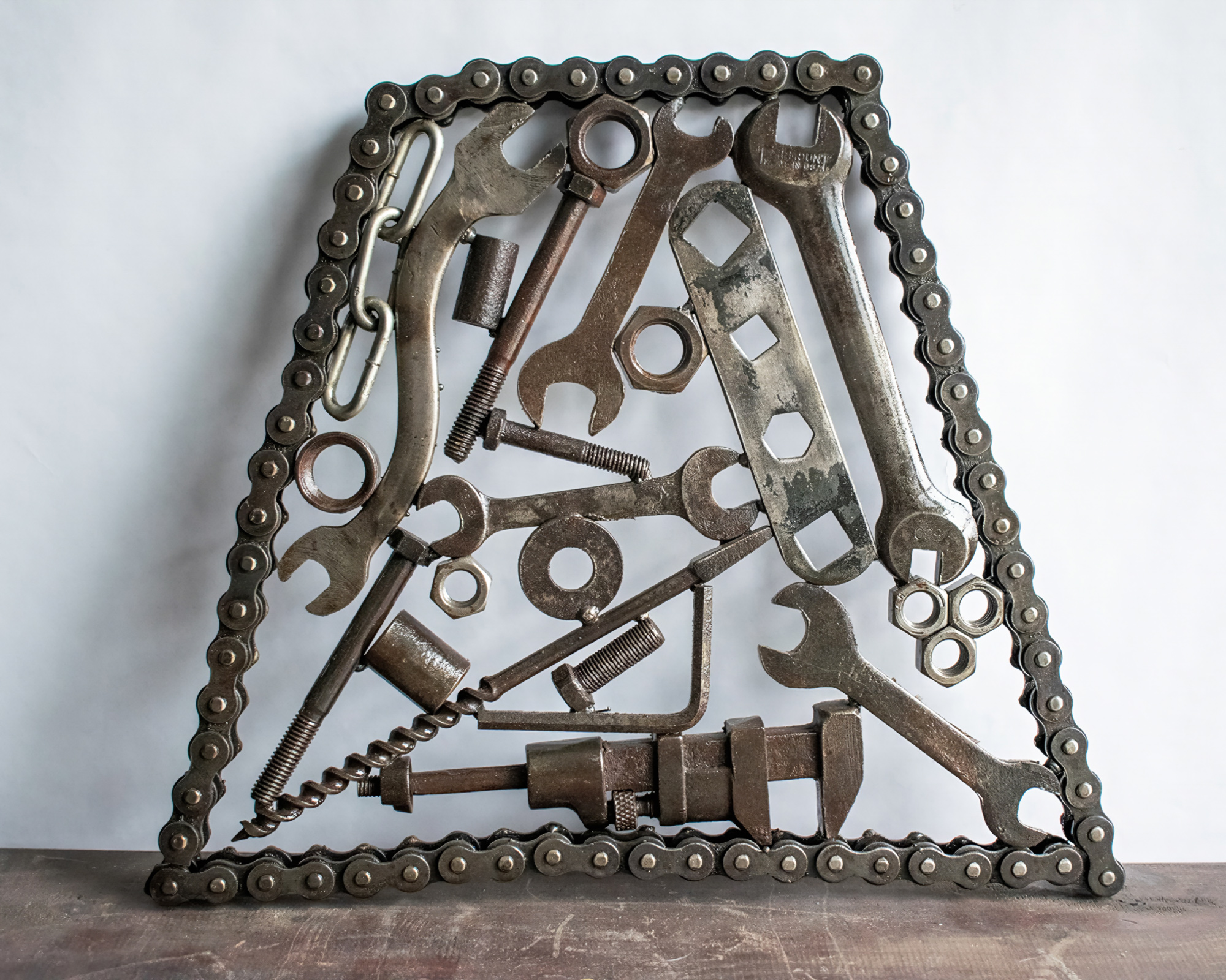 Industrial metal wall art made from motorcycle chain, reclaimed wrenches, nuts, bolts, and steel hardware.