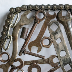 Close-up of welded tool sculpture with motorcycle chain frame, wrenches, bolts, and reclaimed metal parts.