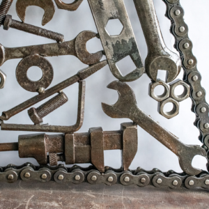 Close-up of reclaimed tool art showing wrenches, nuts, bolts, and motorcycle chain border.