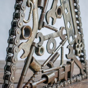 Angled view of industrial metal wall art made from welded tools and motorcycle chain.