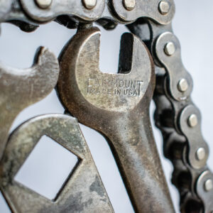 Close-up of wrench detail and motorcycle chain border on industrial welded metal art.