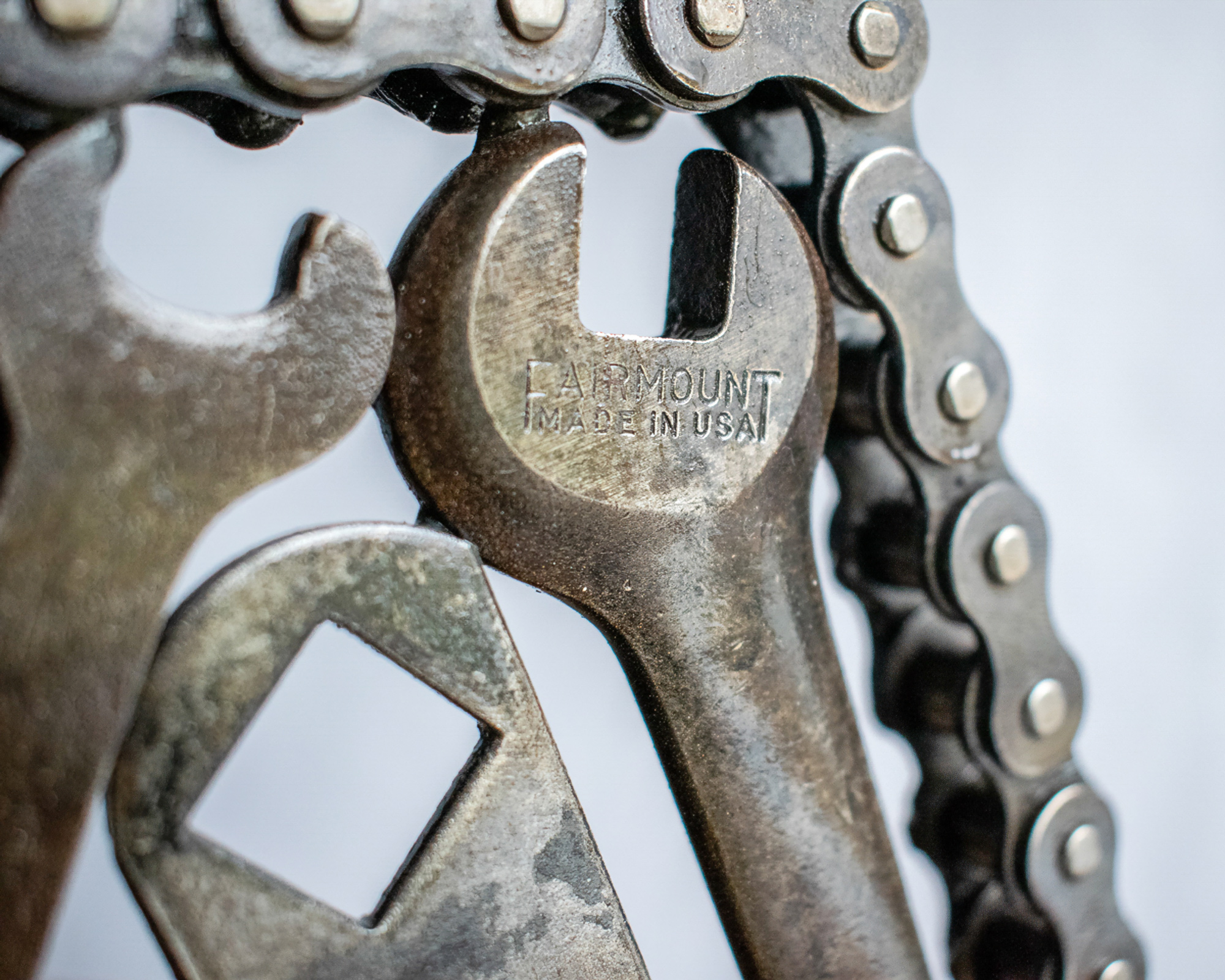 Close-up of wrench detail and motorcycle chain border on industrial welded metal art.