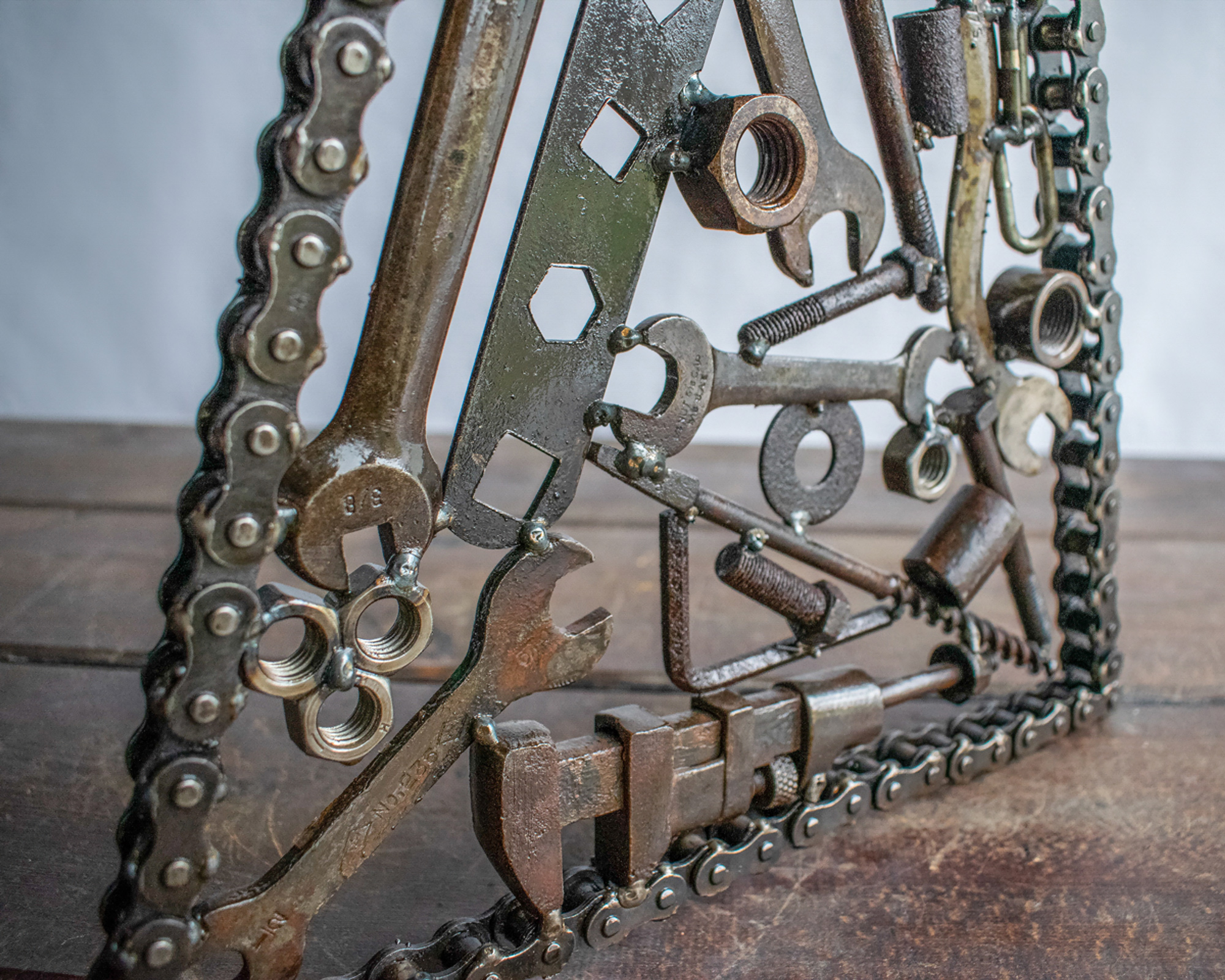 Back view, angled close-up of reclaimed steel hardware and wrenches in a welded tool sculpture.