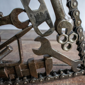 Close-up of nuts, wrenches, and chain frame on a reclaimed metal wall art piece.