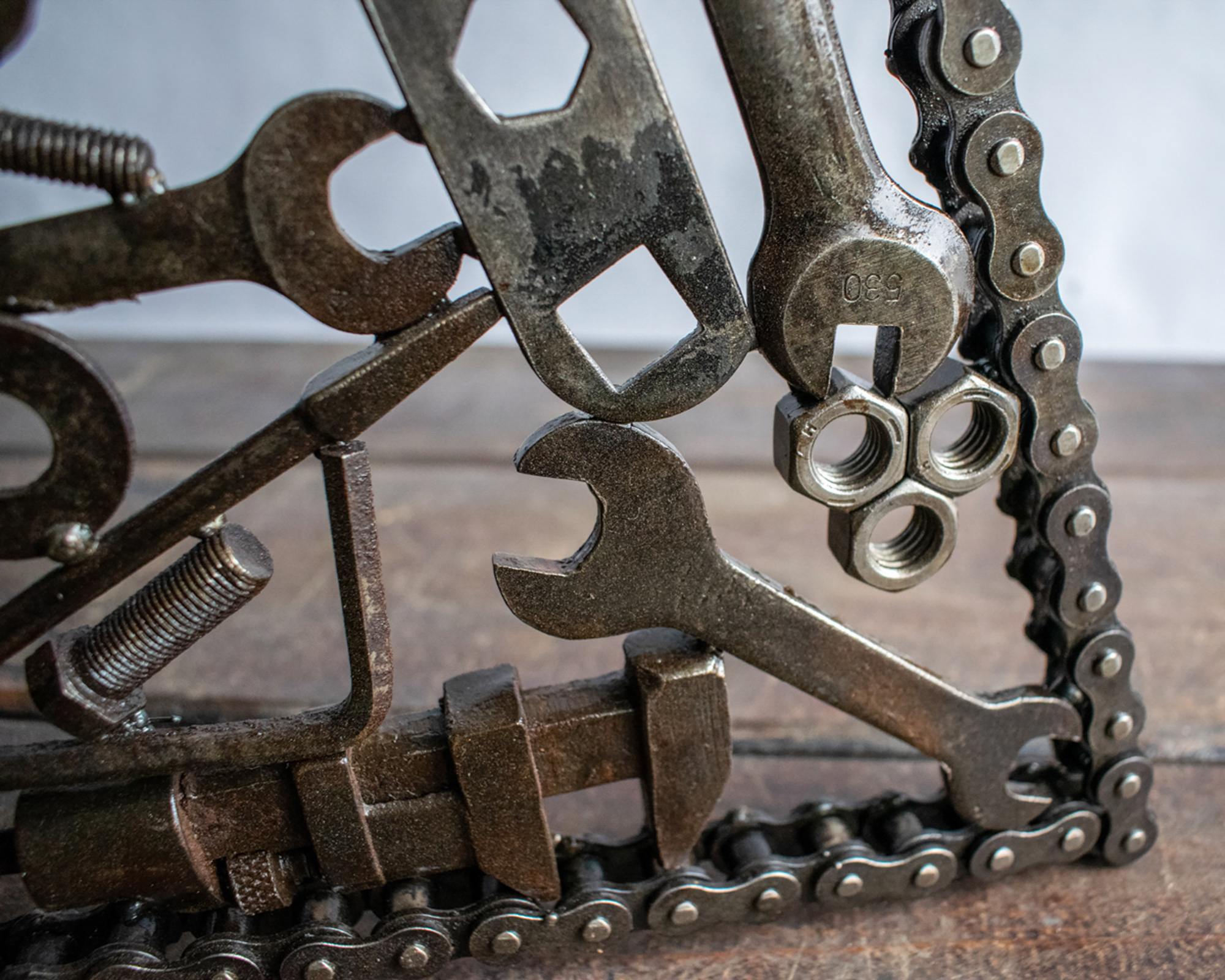 Close-up of nuts, wrenches, and chain frame on a reclaimed metal wall art piece.