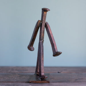Welded railroad spike sculpture of a walking figure made from reclaimed railroad spikes on a steel base.