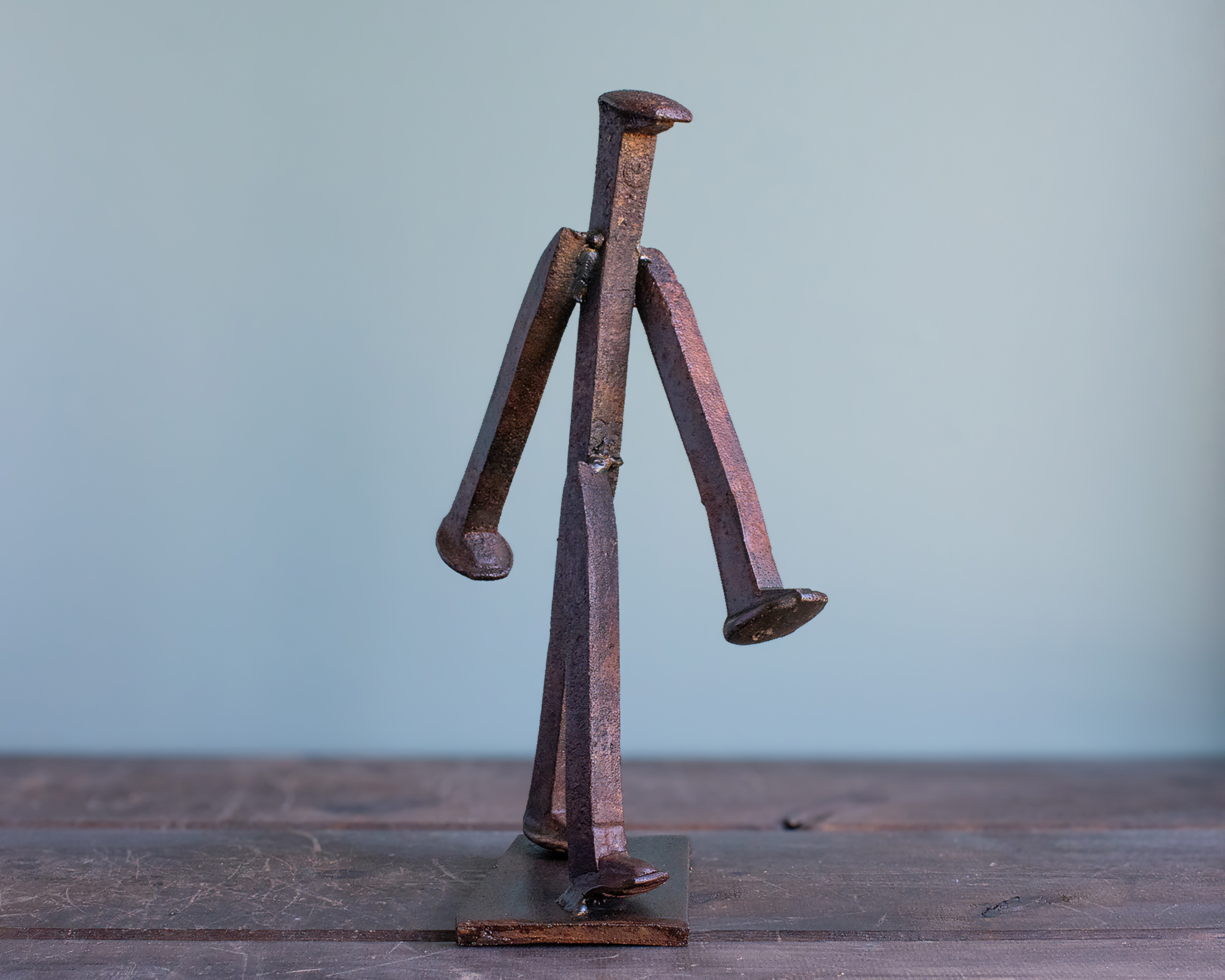 Welded railroad spike sculpture of a walking figure made from reclaimed railroad spikes on a steel base.