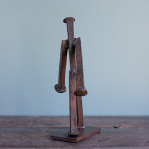 Back view of a welded railroad spike sculpture showing the reclaimed spike body, arms, and legs.