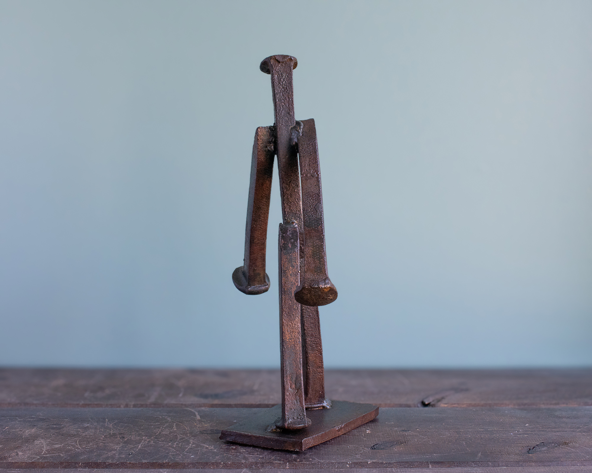 Back view of a welded railroad spike sculpture showing the reclaimed spike body, arms, and legs.