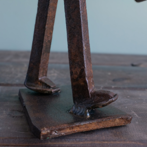 Close-up of railroad spike legs welded to a steel base on an industrial metal sculpture.