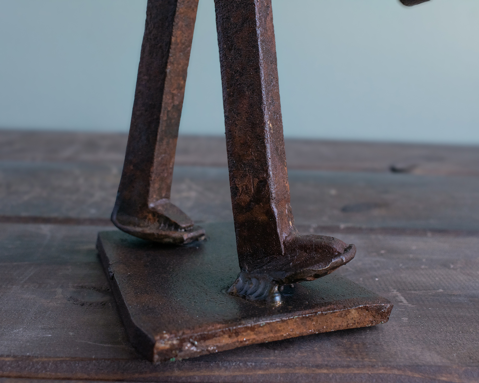 Close-up of railroad spike legs welded to a steel base on an industrial metal sculpture.