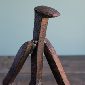 Close-up of the railroad spike head and welded arms on a reclaimed steel sculpture.