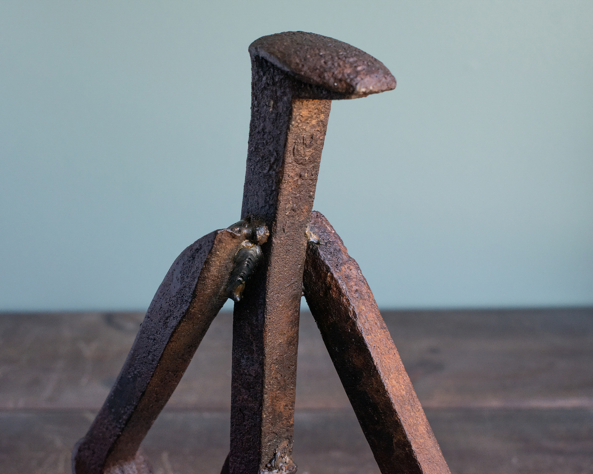 Close-up of the railroad spike head and welded arms on a reclaimed steel sculpture.