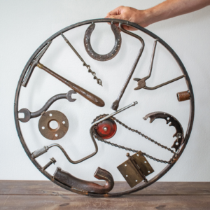 Back view of reclaimed tool art arranged in a circular welded metal wall sculpture.