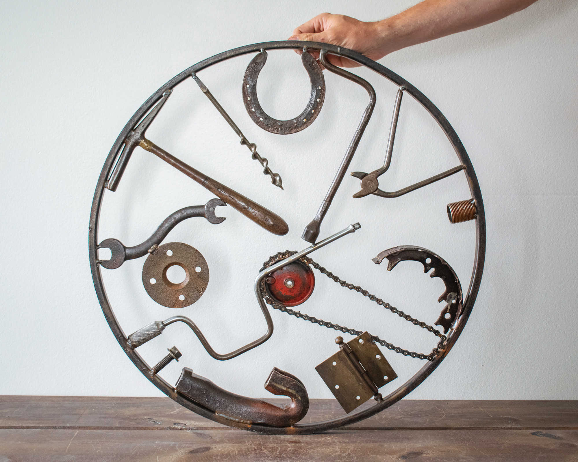 Back view of reclaimed tool art arranged in a circular welded metal wall sculpture.