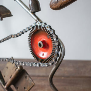Close-up of chain and red metal wheel detail on a welded metal wall art sculpture.