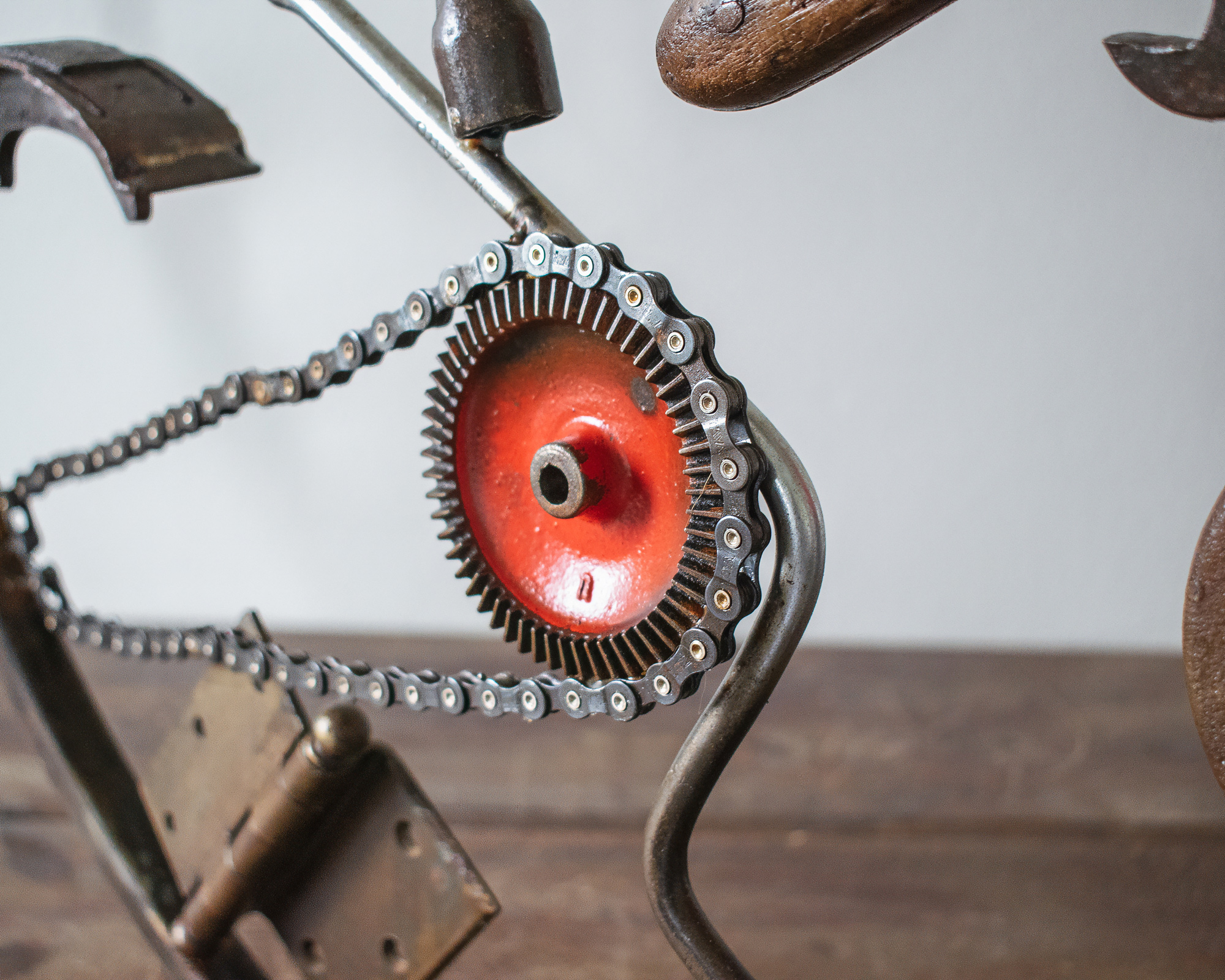 Close-up of chain and red metal wheel detail on a welded metal wall art sculpture.