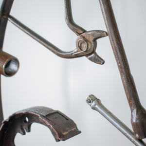 Close-up of reclaimed tool parts in an industrial welded tool sculpture, including pliers and metal rods.