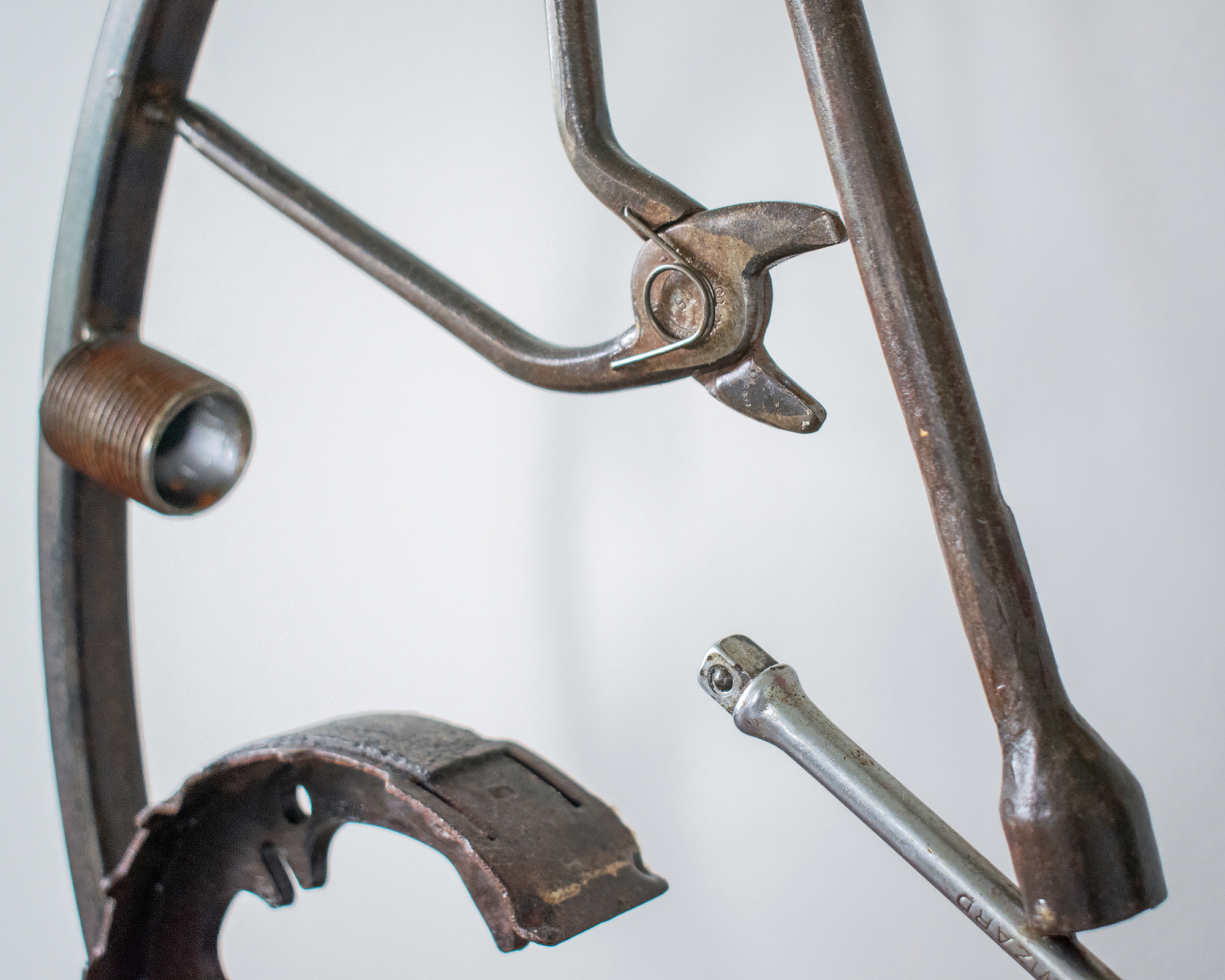 Close-up of reclaimed tool parts in an industrial welded tool sculpture, including pliers and metal rods.